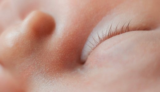 Macro photo of closed eye of sleeping newborn baby girl. Horizontal close-up image.